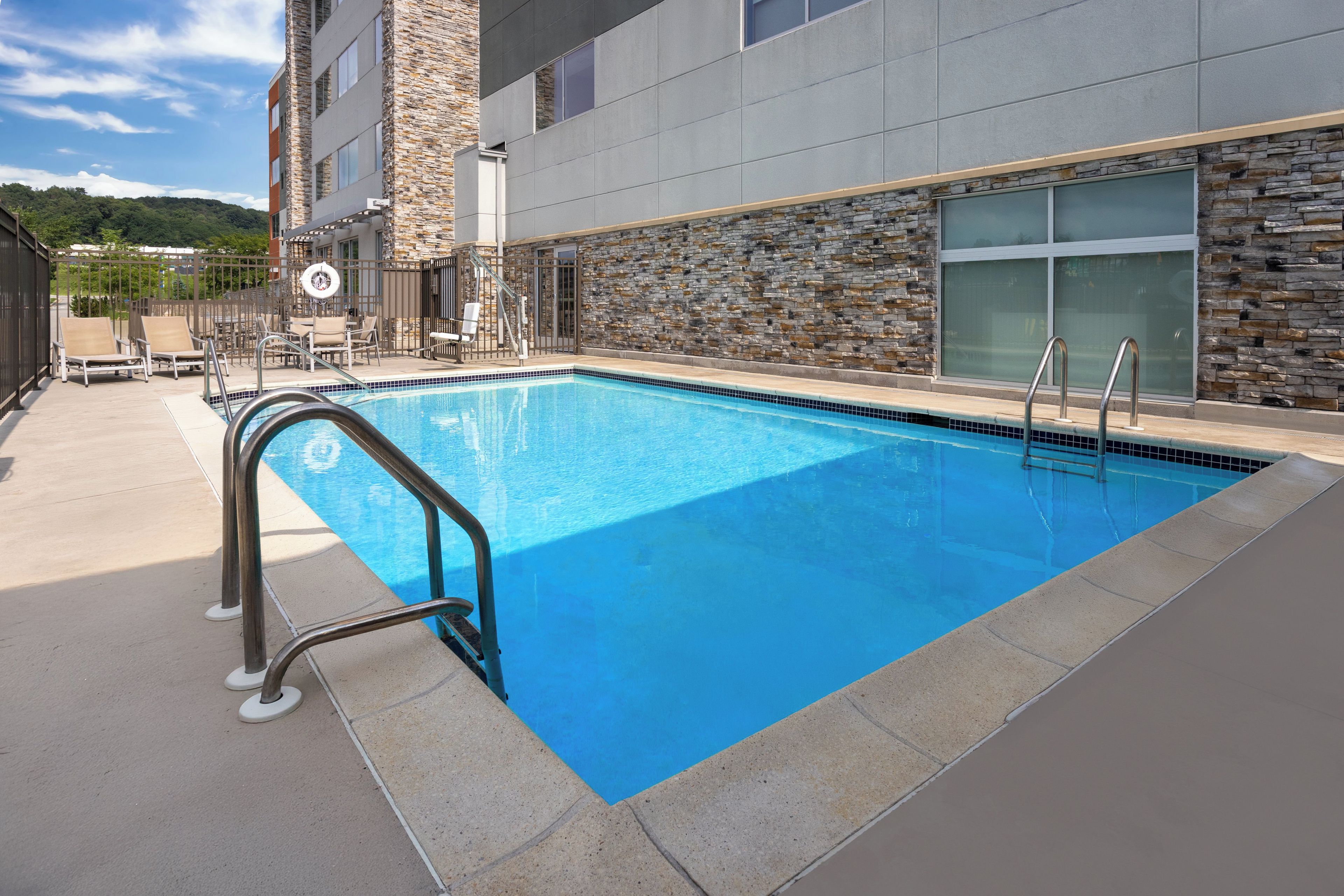 Una piscina con fachada de piedra y barandillas metálicas.