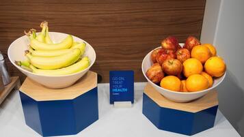 Two bowls of fruit on a counter with a sign that reads 'GO ON, TREAT YOUR HEALTH'.