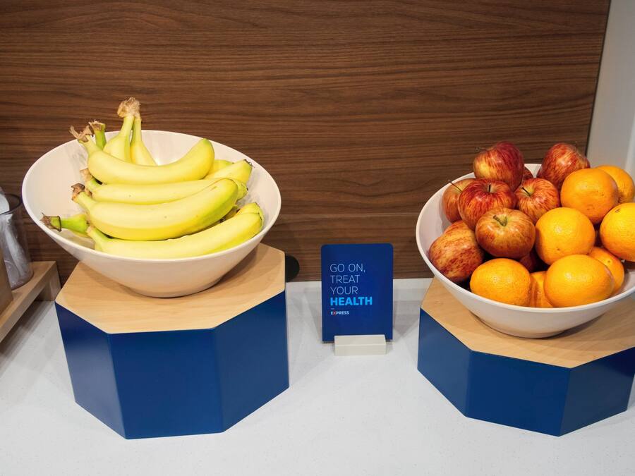 Two bowls of fruit on a counter with a sign that reads 'GO ON, TREAT YOUR HEALTH'.