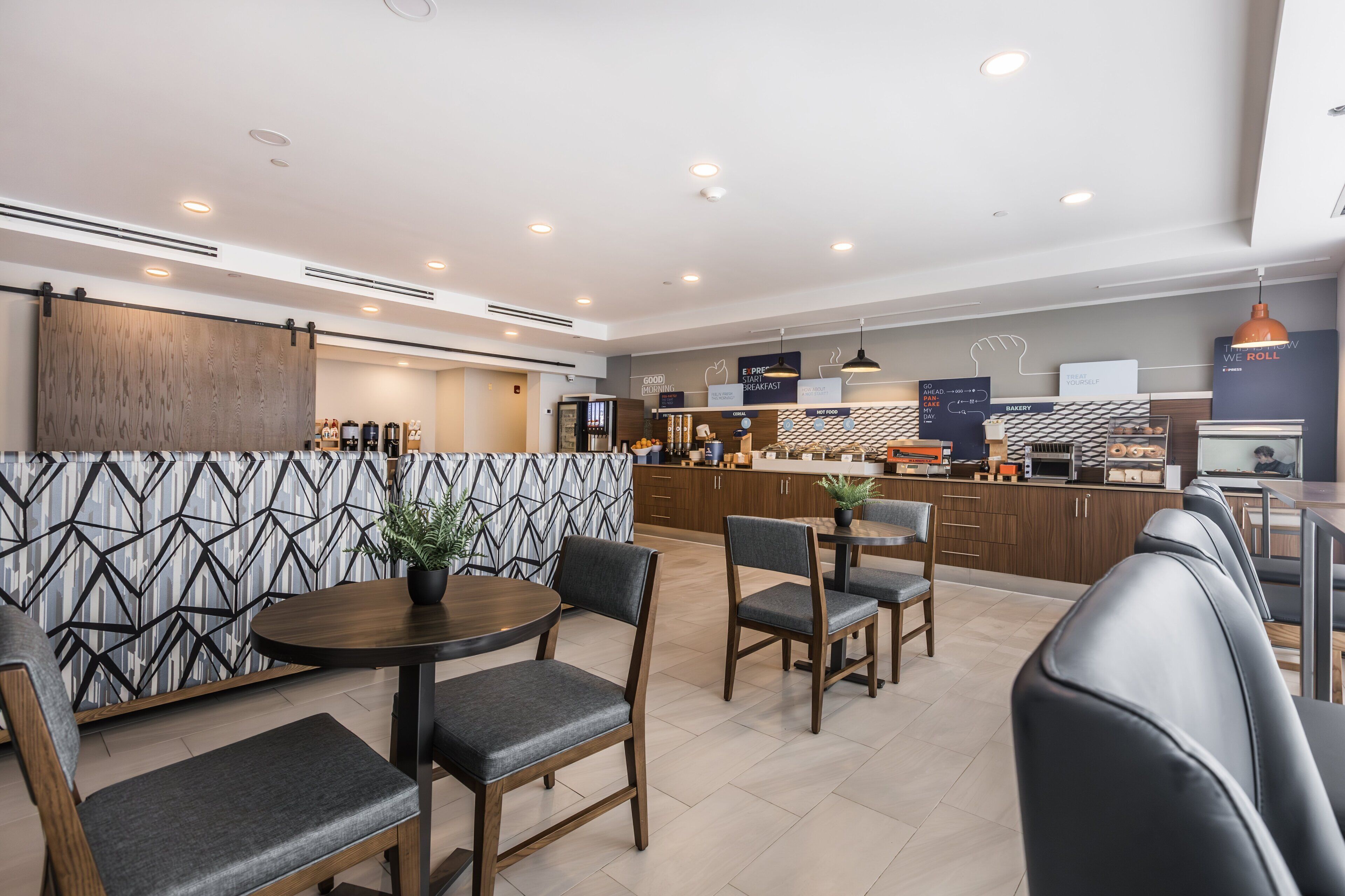 Un restaurante moderno con barra, asientos y cocina al fondo.