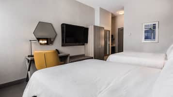 Habitación de hotel con dos camas, un escritorio con una silla, un televisor de pantalla plana montado en la pared y un cuadro enmarcado.