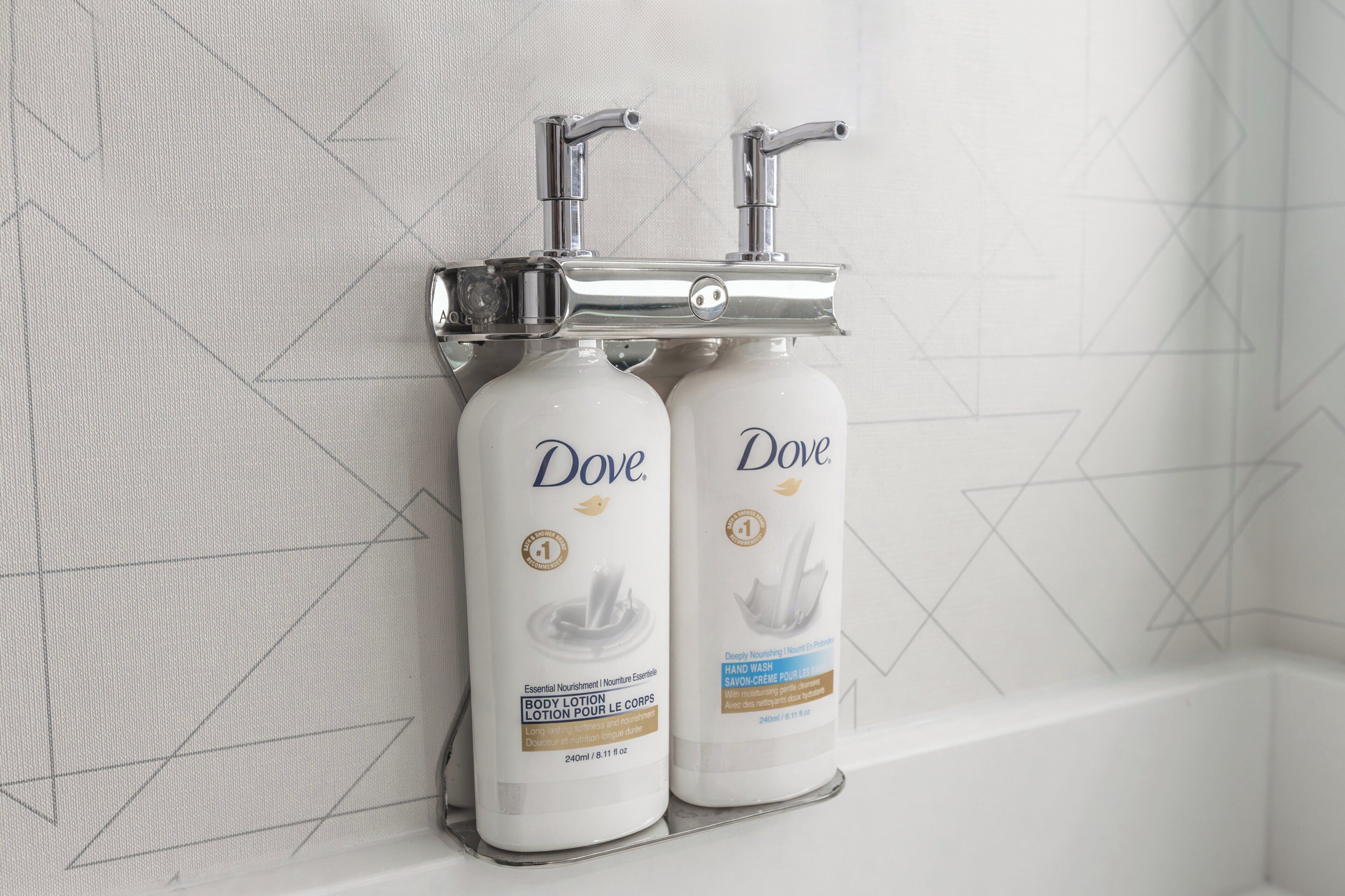 Two Dove body lotion bottles mounted on a wall with a geometric pattern.
