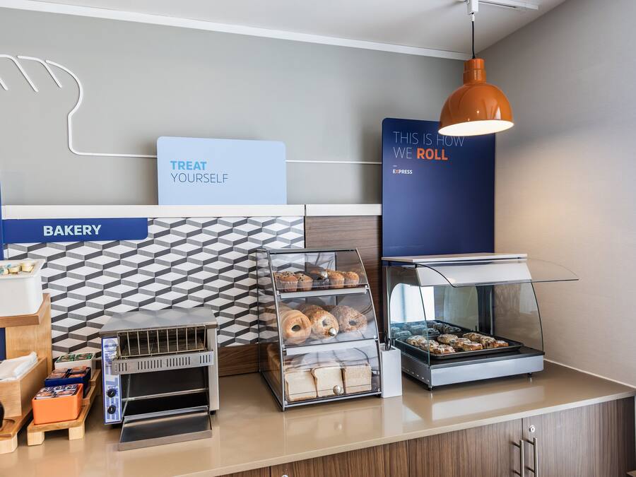 Mostrador de panadería con vitrina, un tostador y un letrero que dice 'THIS IS HOW WE ROLL'.