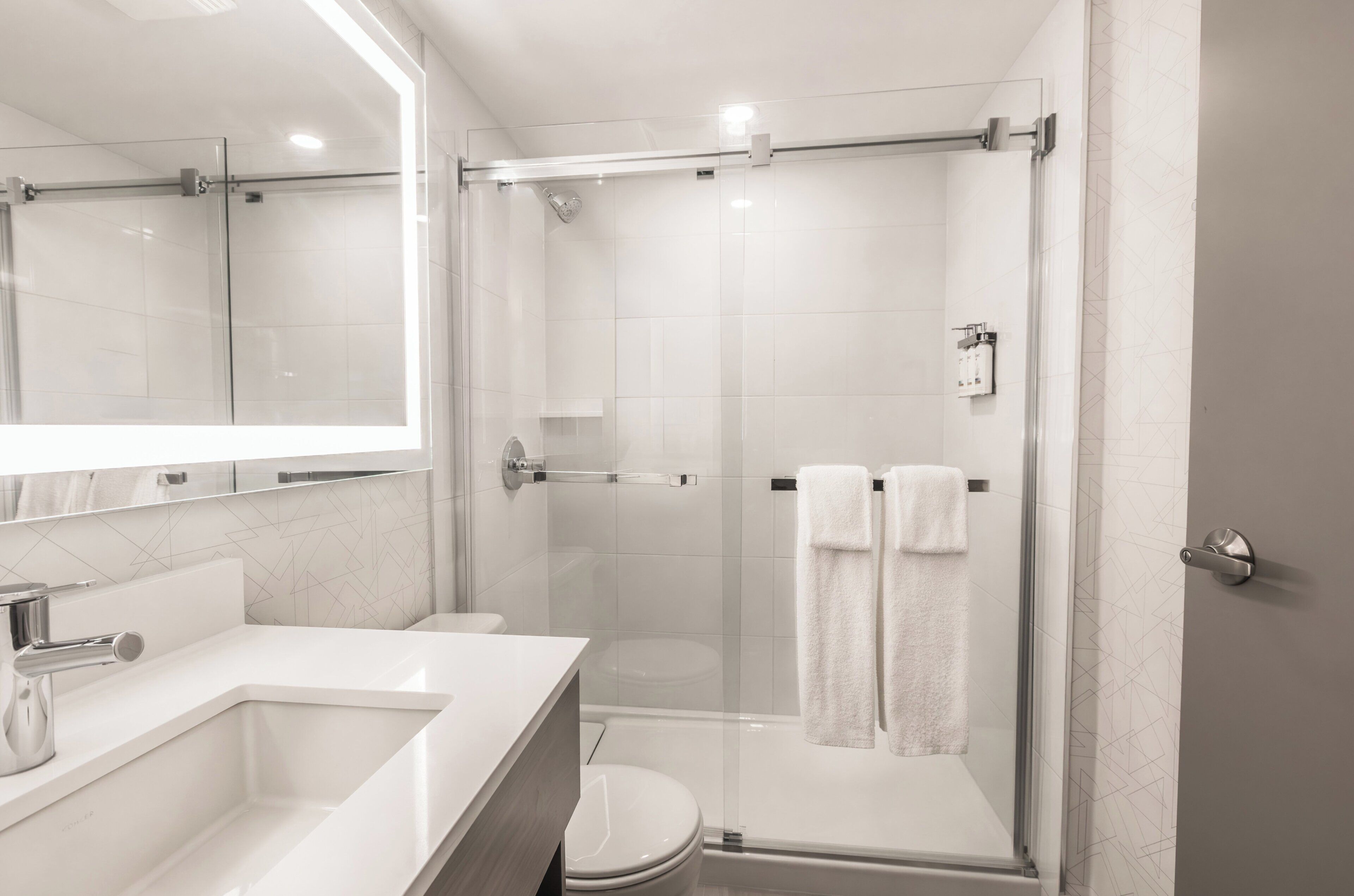Un baño moderno con ducha de vidrio, inodoro y lavamanos.