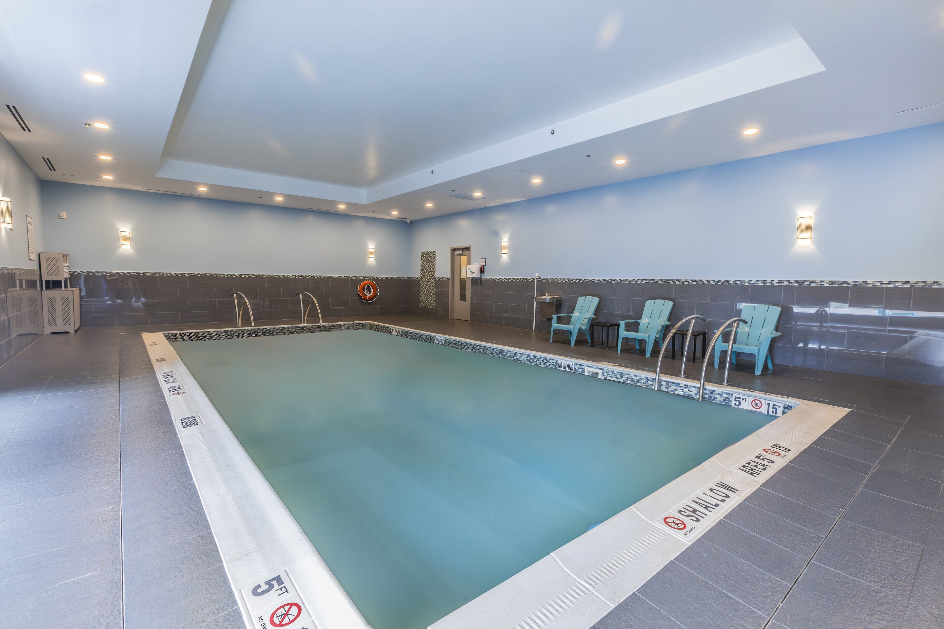 A swimming pool with a tiled deck, a lifeguard chair, and a no diving sign.