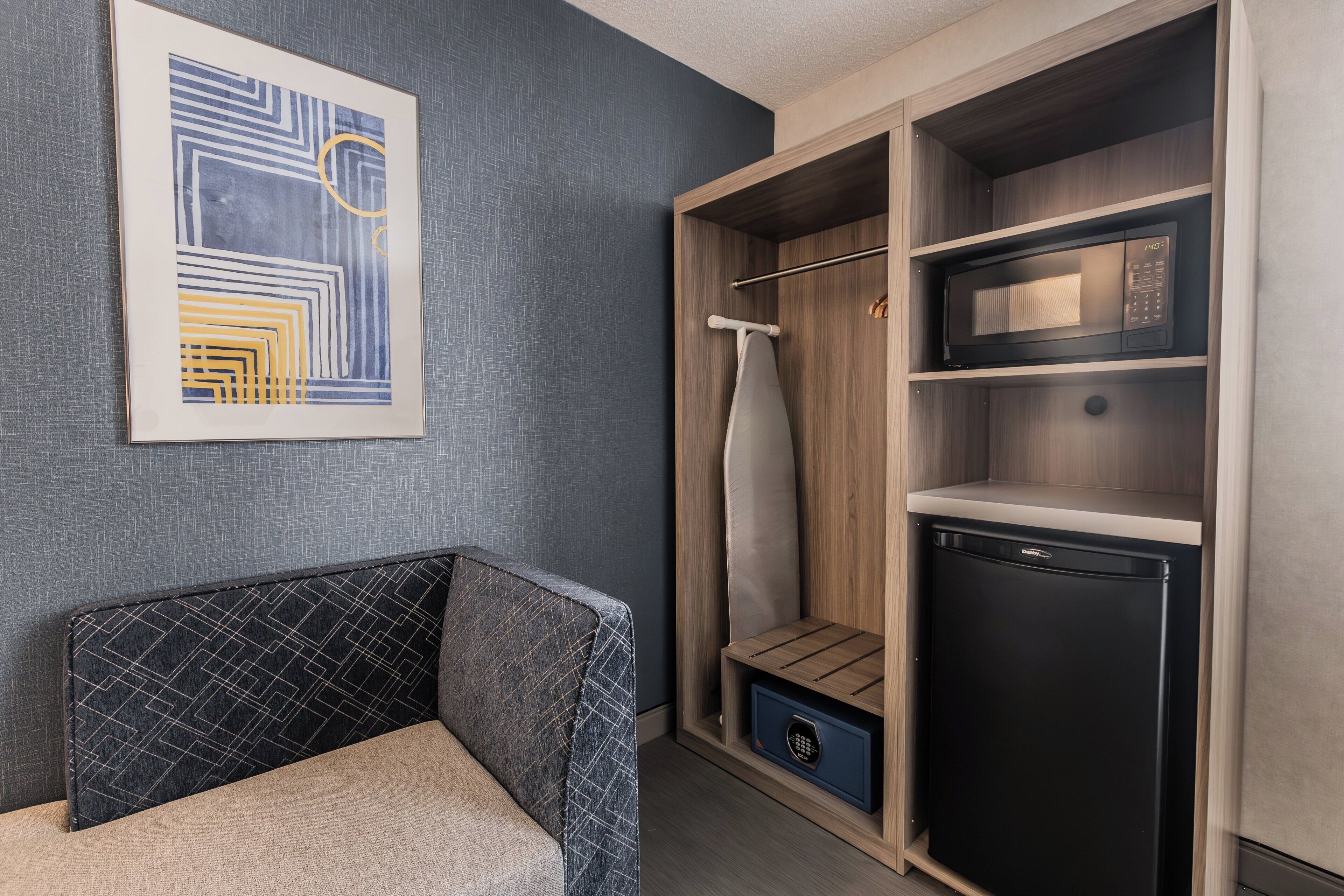 Habitación pequeña con cama, armario y electrodoméstico.