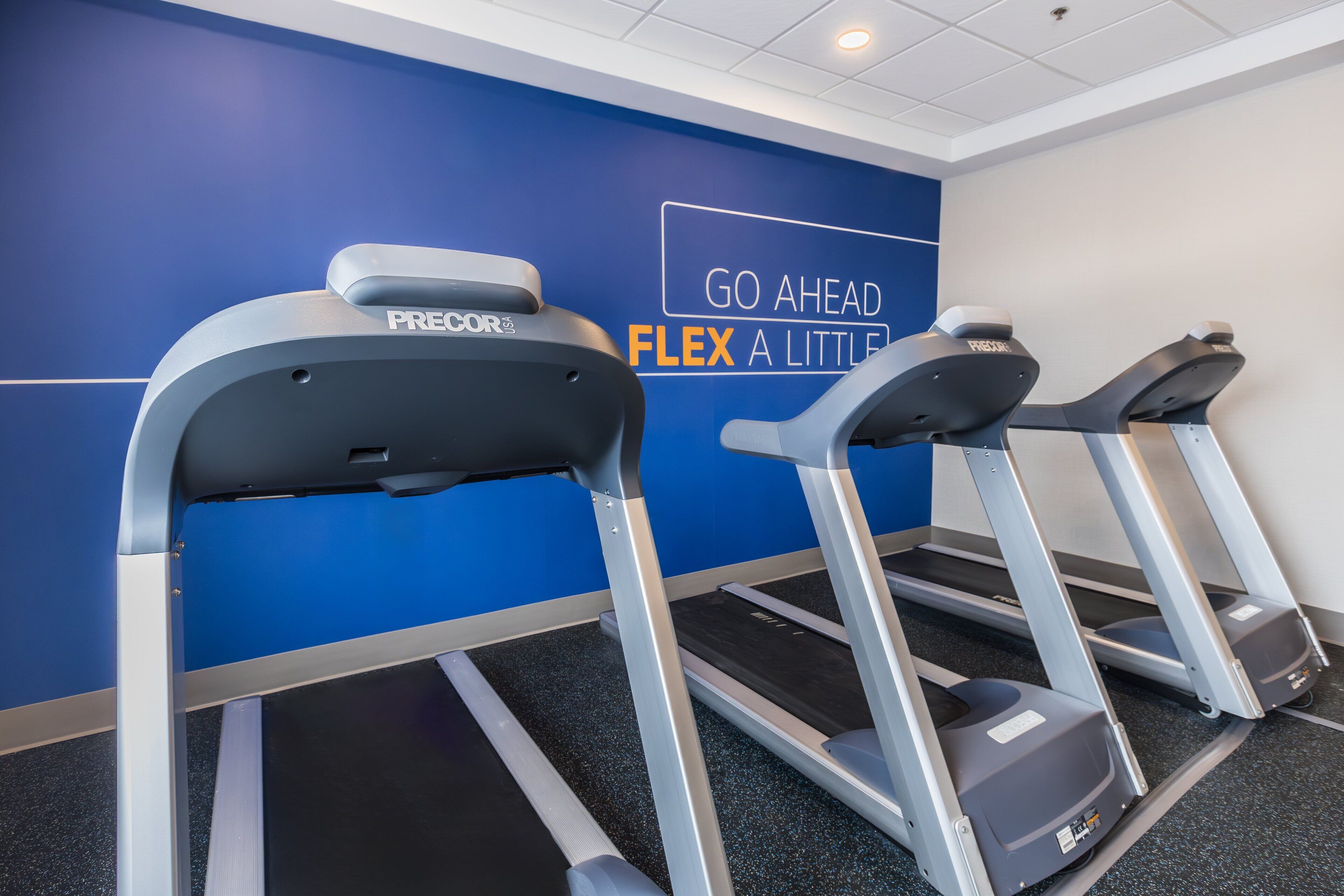 A gym with treadmills and a motivational wall.