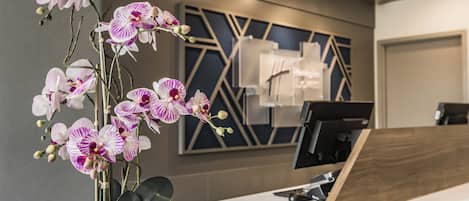 Un mostrador de recepción con una orquídea en maceta al frente.