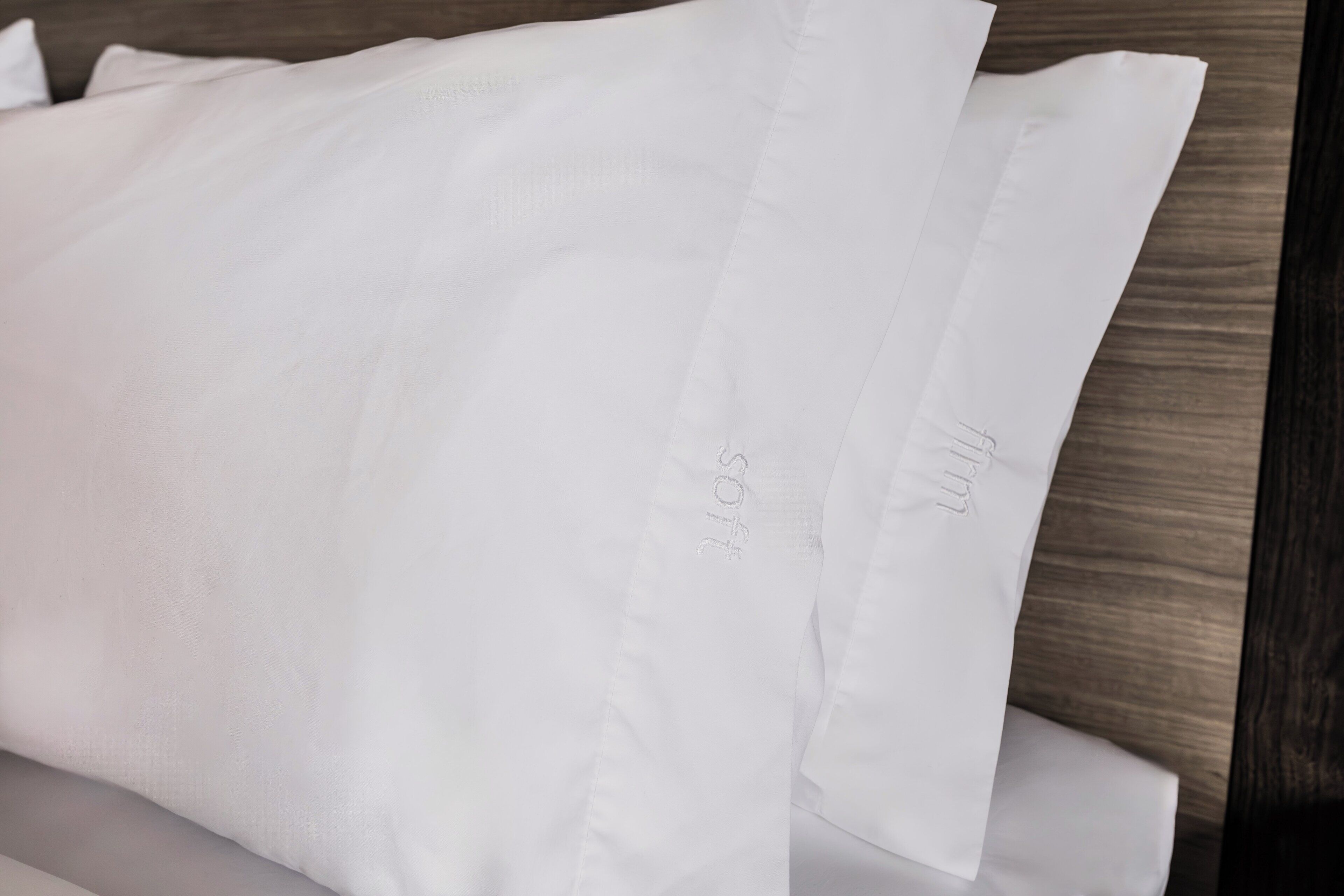 A white pillow with the text 'SOFT' and 'SOFT' on it, placed on a wooden surface.