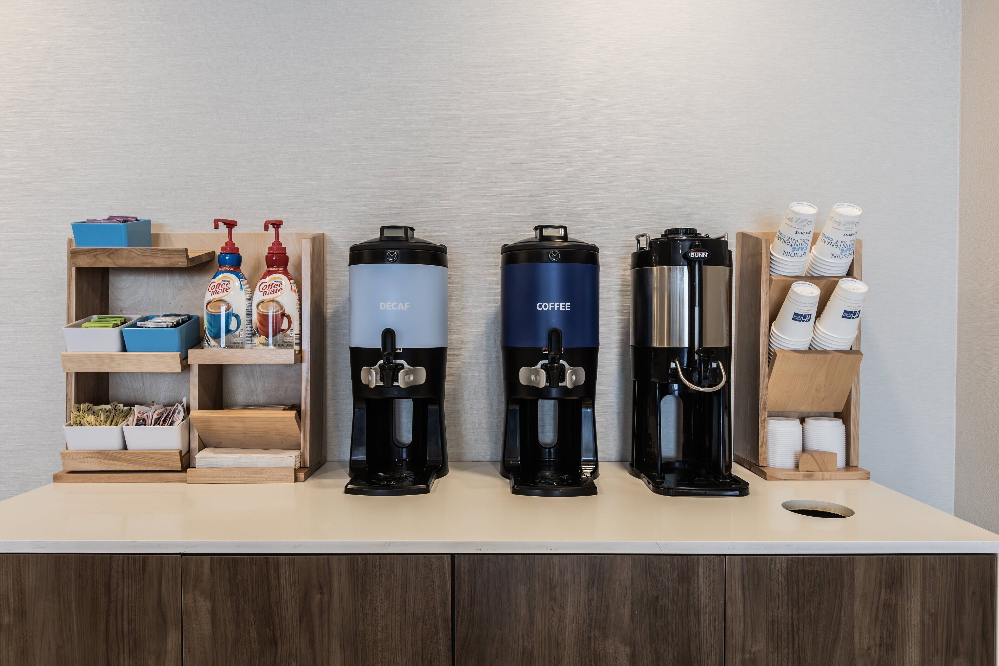 A coffee station with four coffee makers and a coffee dispenser.