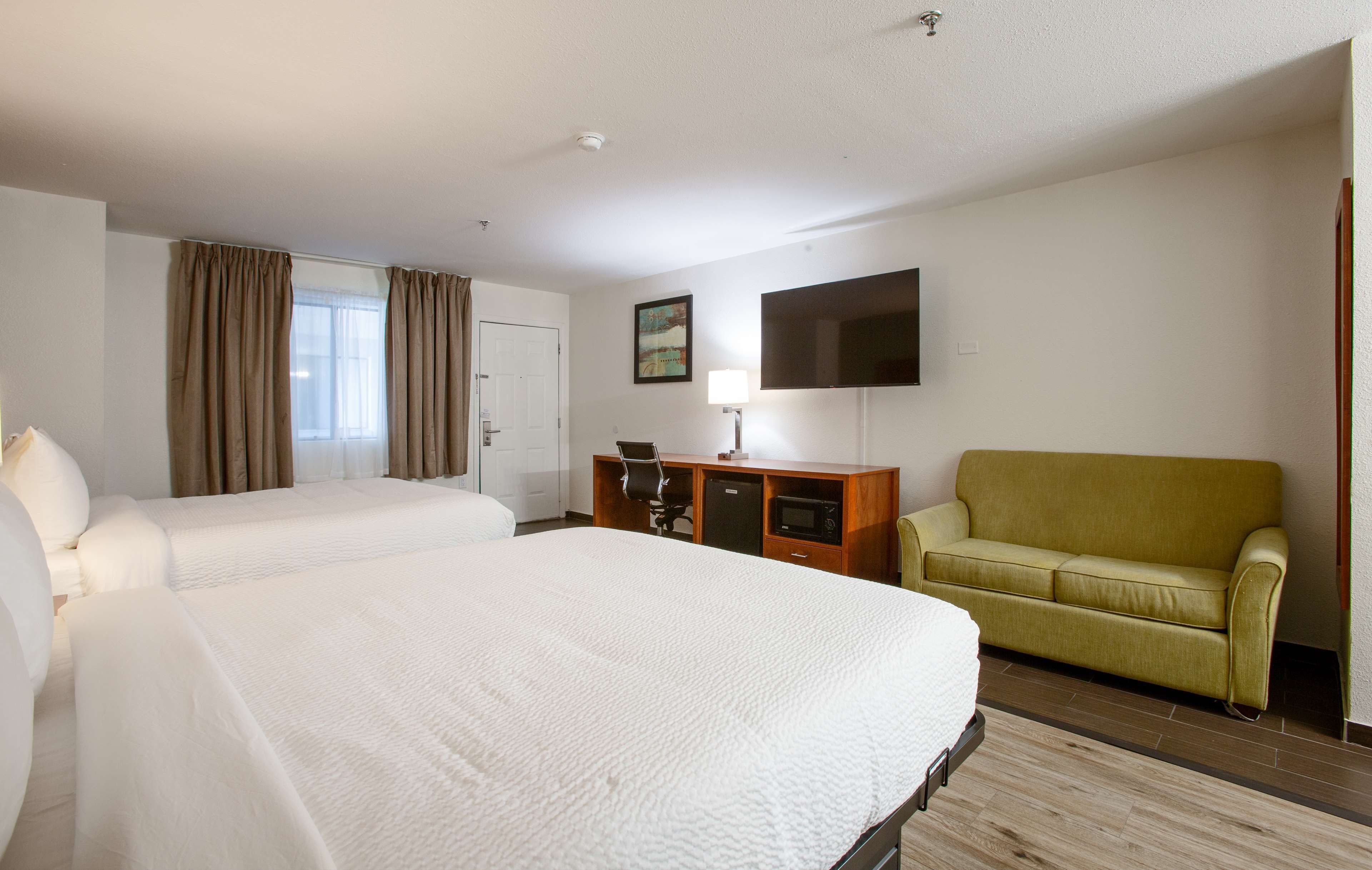 Een hotelkamer met twee bedden, een bureau, een televisie en een bank.