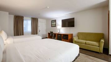Een hotelkamer met twee bedden, een bureau, een televisie en een bank.