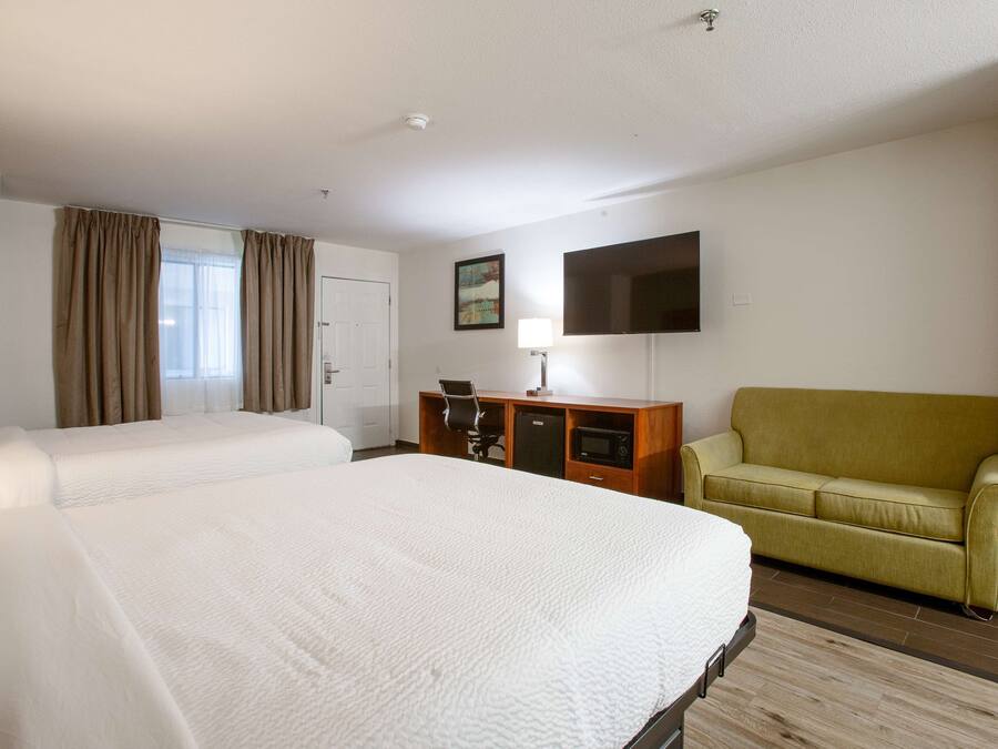 Een hotelkamer met twee bedden, een bureau, een televisie en een bank.