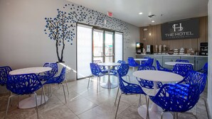 A hotel lobby with blue chairs and tables, a tree mural, and a sign reading "The Hotel Serene". - The Hotel Serene Glendale Peoria, Surestay Collection by BW (Glendale)