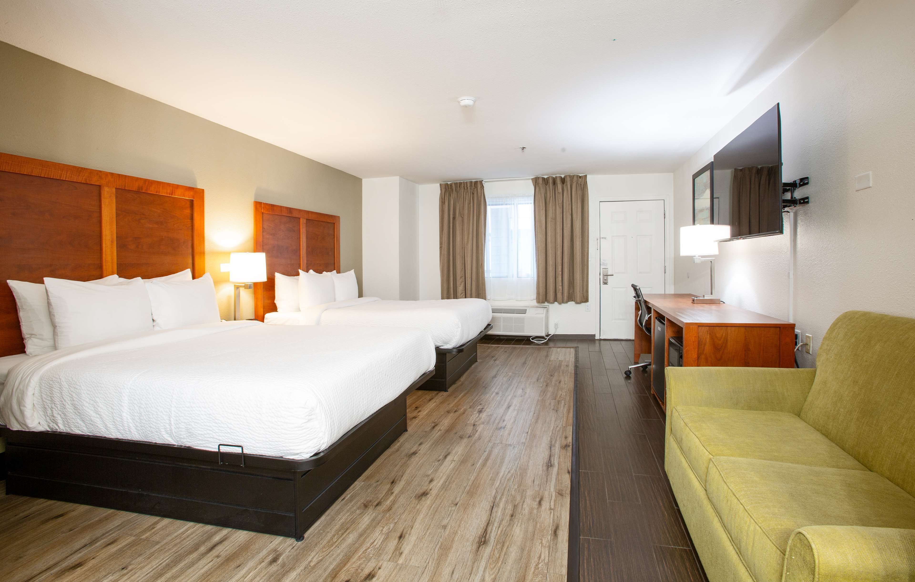 A hotel room with a large bed, a sofa, a desk, and a TV.