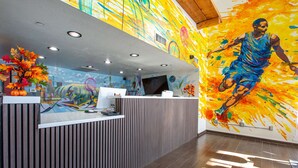 A reception desk with a modern design, a large mural on the wall, and a wooden floor. - The Hotel Serene Glendale Peoria, Surestay Collection by BW (Glendale)