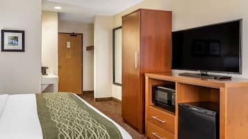 A hotel room with a bed, a wooden wardrobe, a television, a microwave, and a refrigerator.