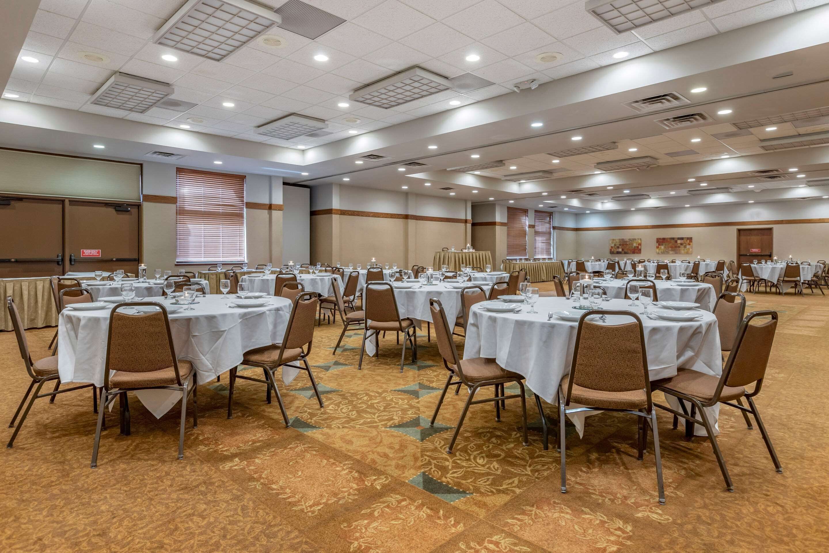 A large banquet hall with round tables set for dining, equipped with chairs and table settings.