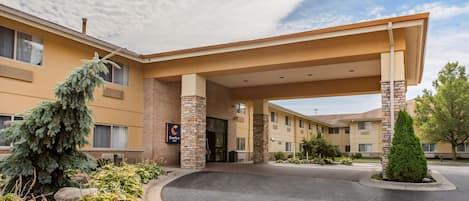 A hotel entrance with a covered driveway, brick pillars, and a sign indicating the hotel name.