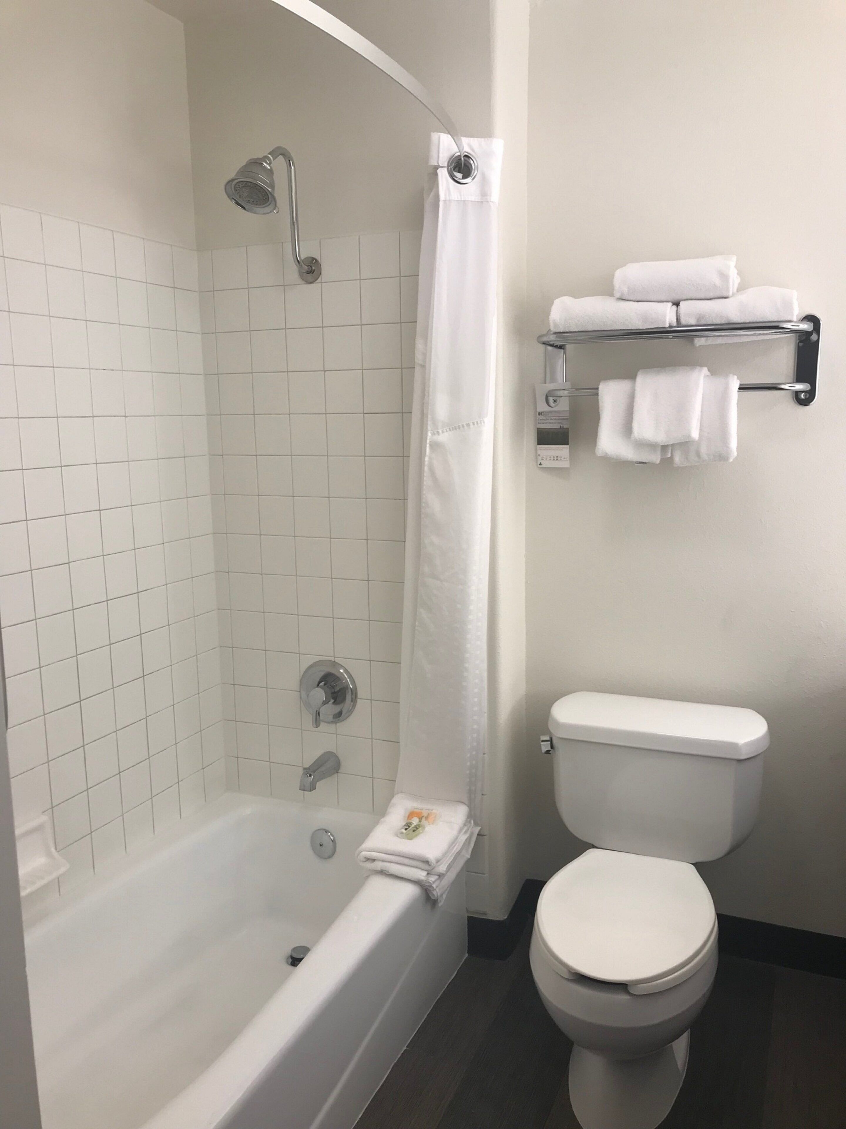 Uma casa de banho com banheira, chuveiro, sanita e um porta-toalhas com toalhas.