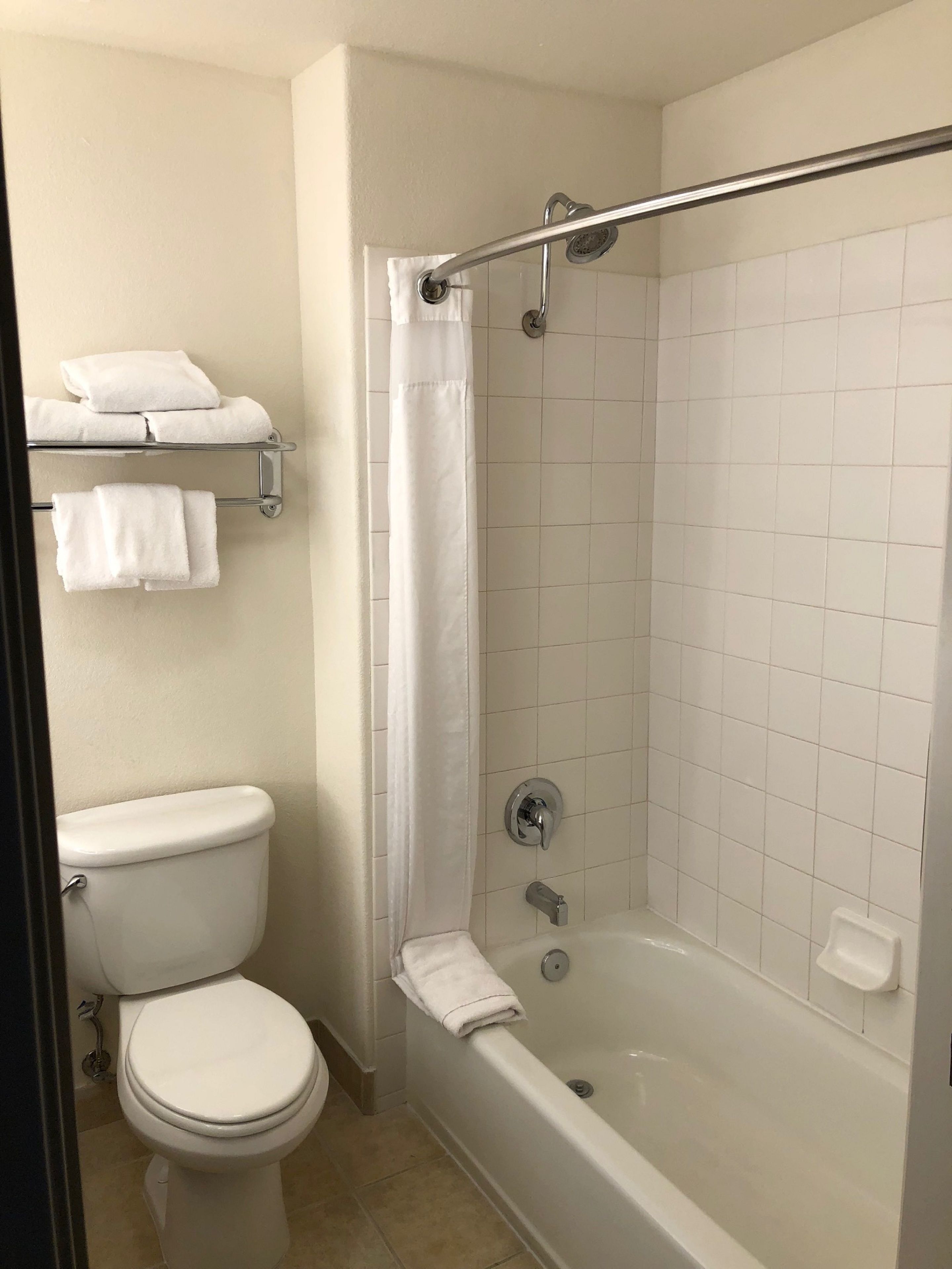 A bathroom with a toilet, a shower with a glass door, and a towel rack with towels.