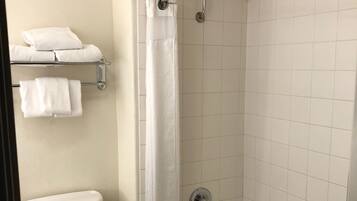 A bathroom with a toilet, a shower with a glass door, and a towel rack with towels.