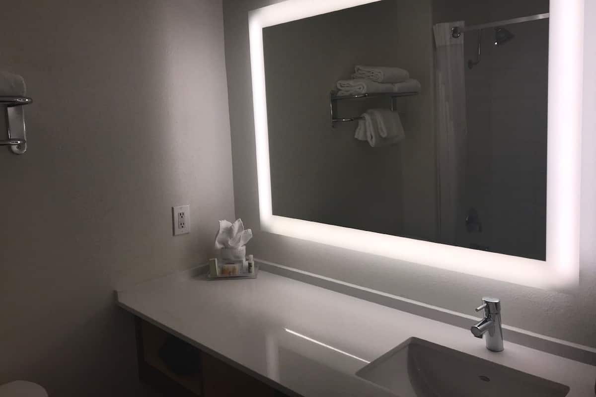 Ein modernes Badezimmer mit großem Spiegel, Waschbecken und Handtuchhalter.
