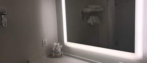 Um banheiro moderno com um espelho grande, uma pia e um porta-toalhas.