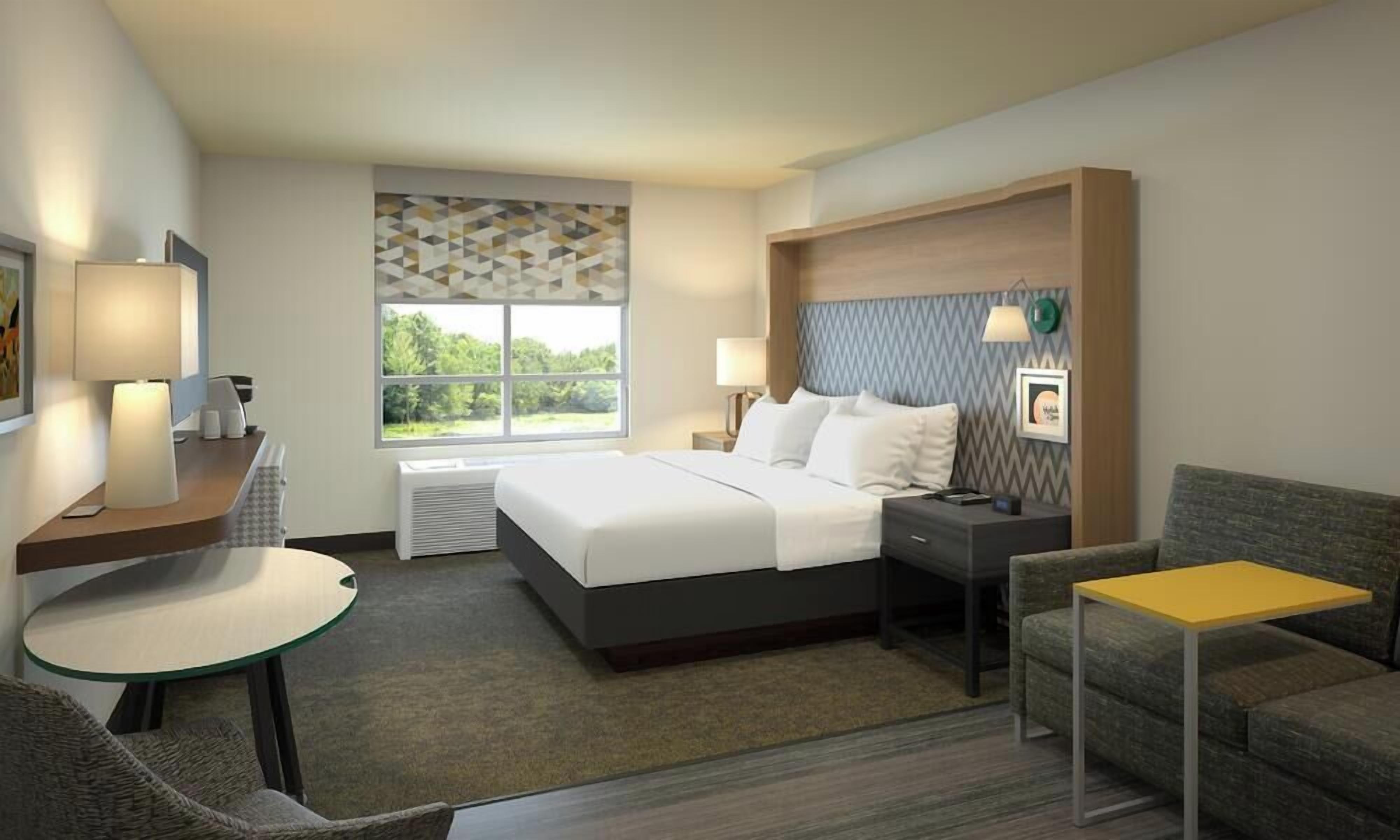 Een hotelkamer met een bed, een bureau, een stoel, een klein tafeltje en een bank.