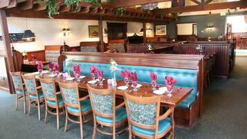 A restaurant with wooden booths and tables, blue cushioned chairs, and a patterned wall.