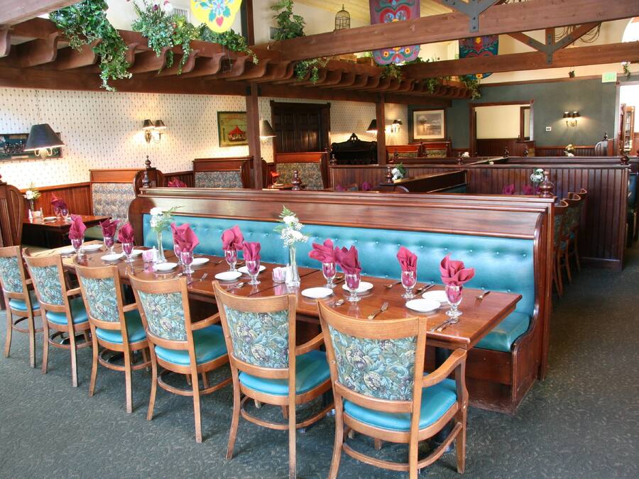 A restaurant with wooden booths and tables, blue cushioned chairs, and a patterned wall.