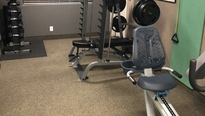 Ein Fitnessraum mit Gewichteinrichtung, einer Bank und einem Wandbild.