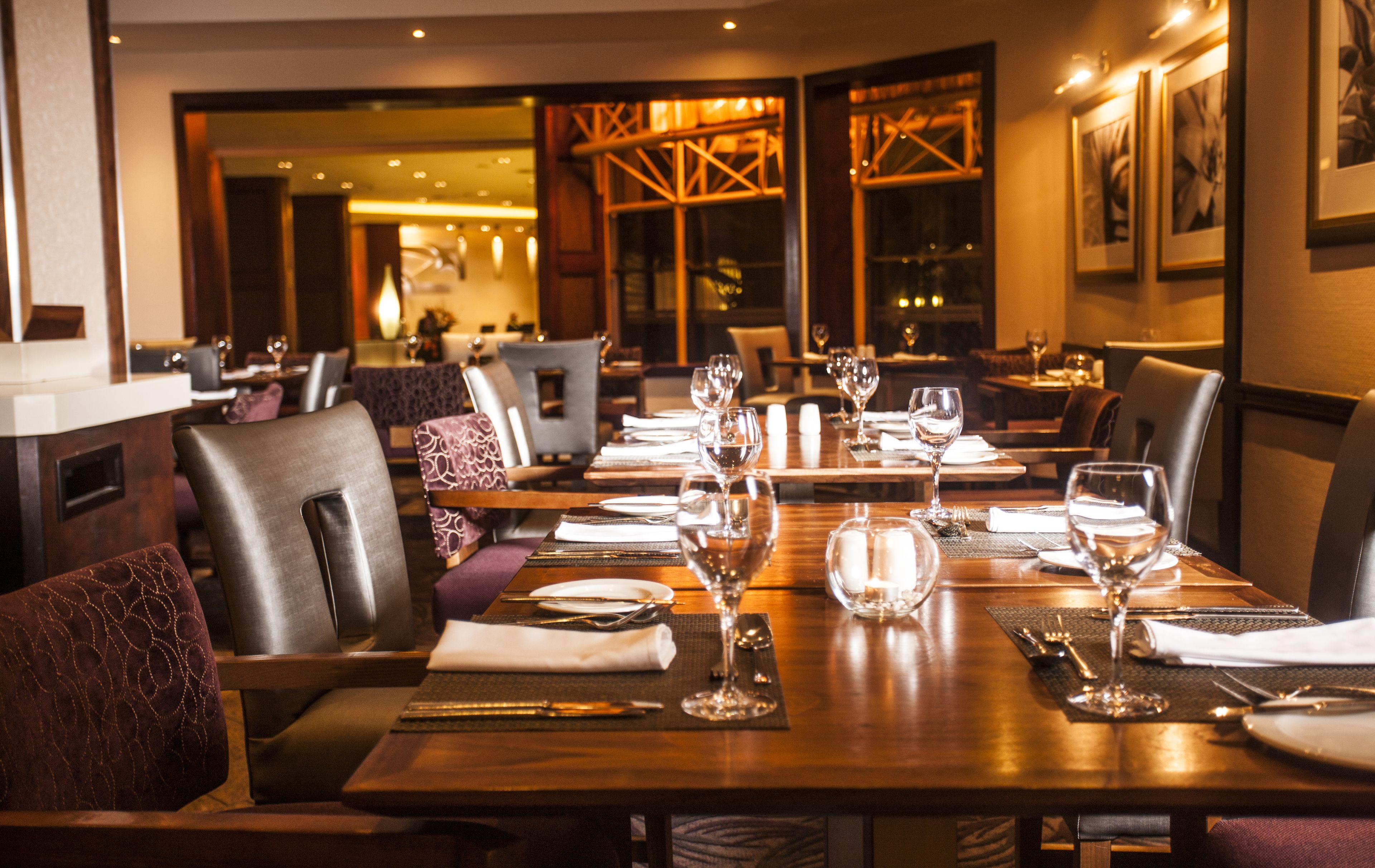A restaurant with wooden tables set for dining, including wine glasses and cutlery.