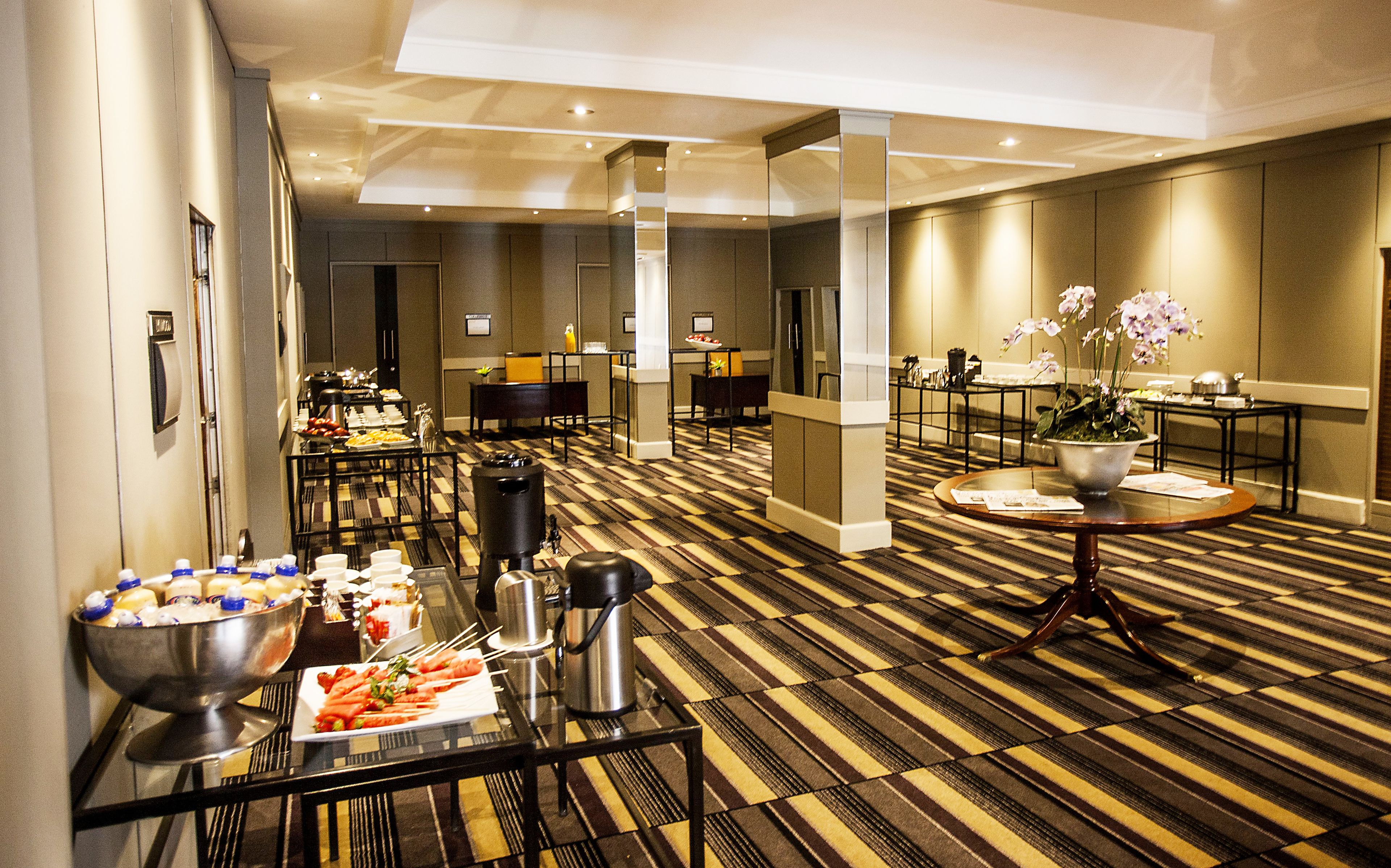 A hotel lobby with a buffet table, a coffee station, and a reception desk.