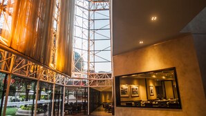 A spacious lobby with a high ceiling, a grand piano, and a modern reception desk.