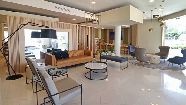 A modern hotel lobby with a sofa, round tables, and chairs.