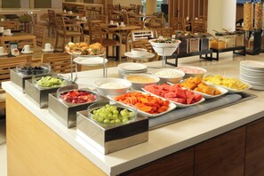 A buffet with various food items and a seating area with wooden tables and chairs. - Holiday Inn Tijuana Zona Rio by IHG (Tijuana)