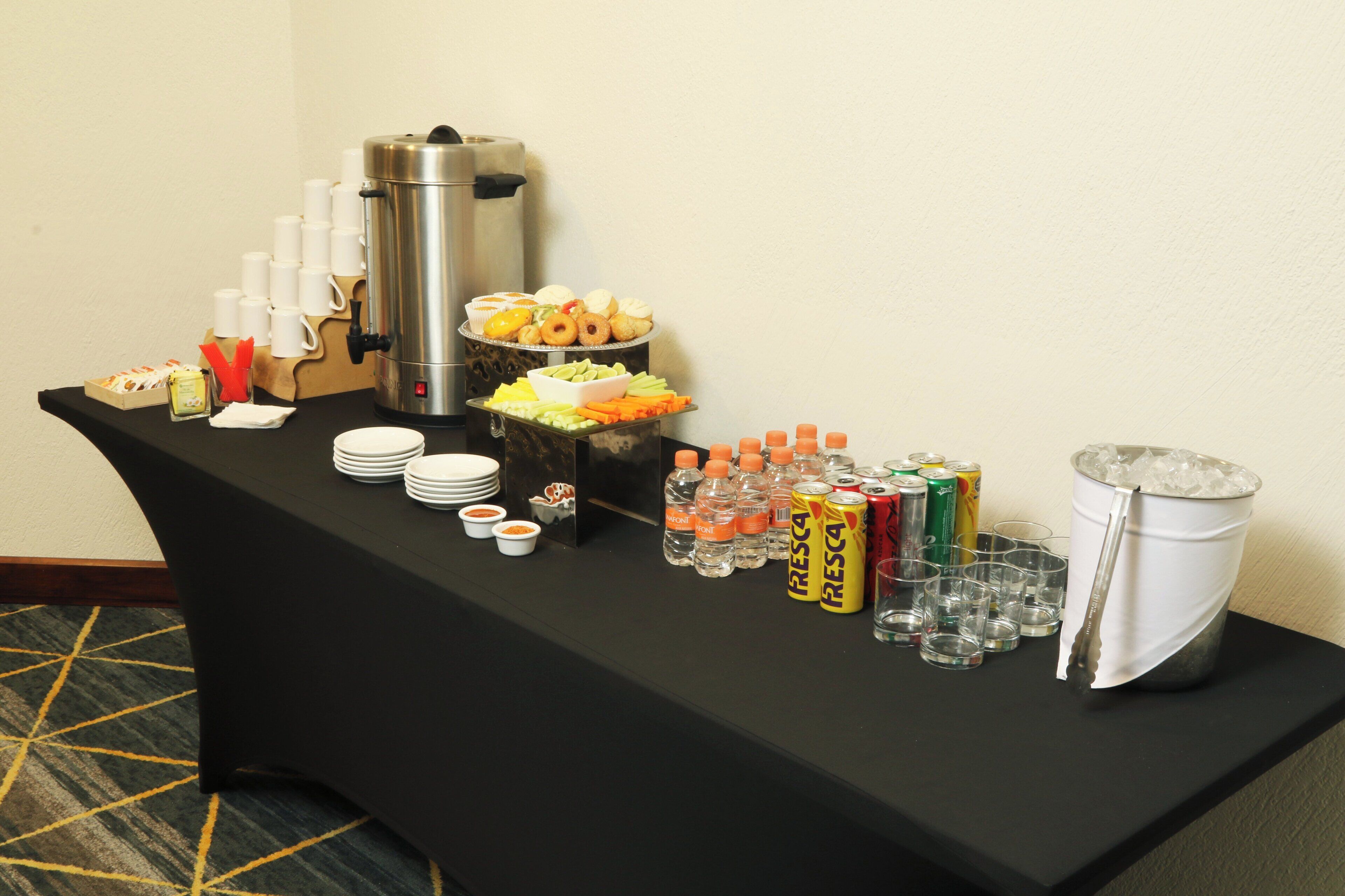 A buffet table with a coffee maker, various food items, and beverages.