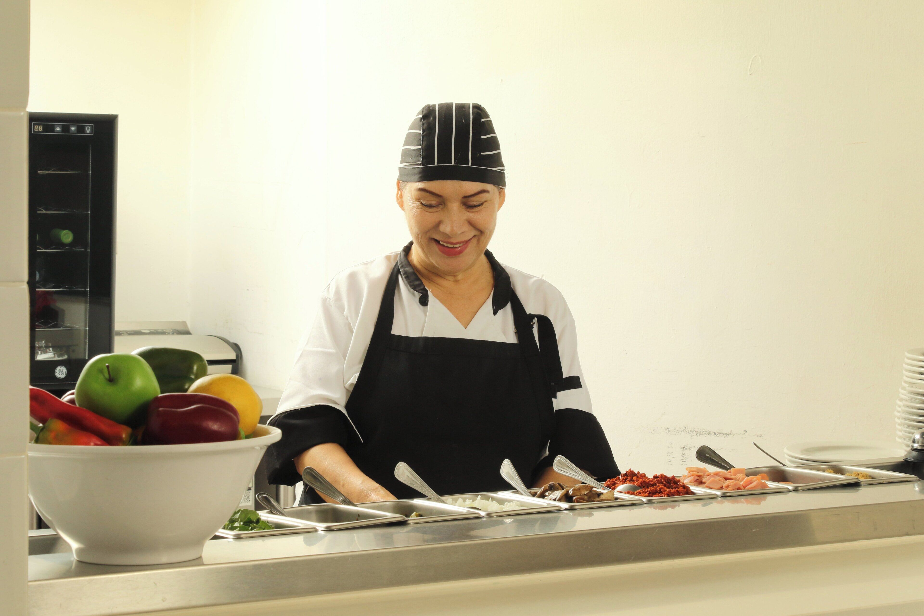 Una persona con uniforme de chef preparando comida en un bufé.