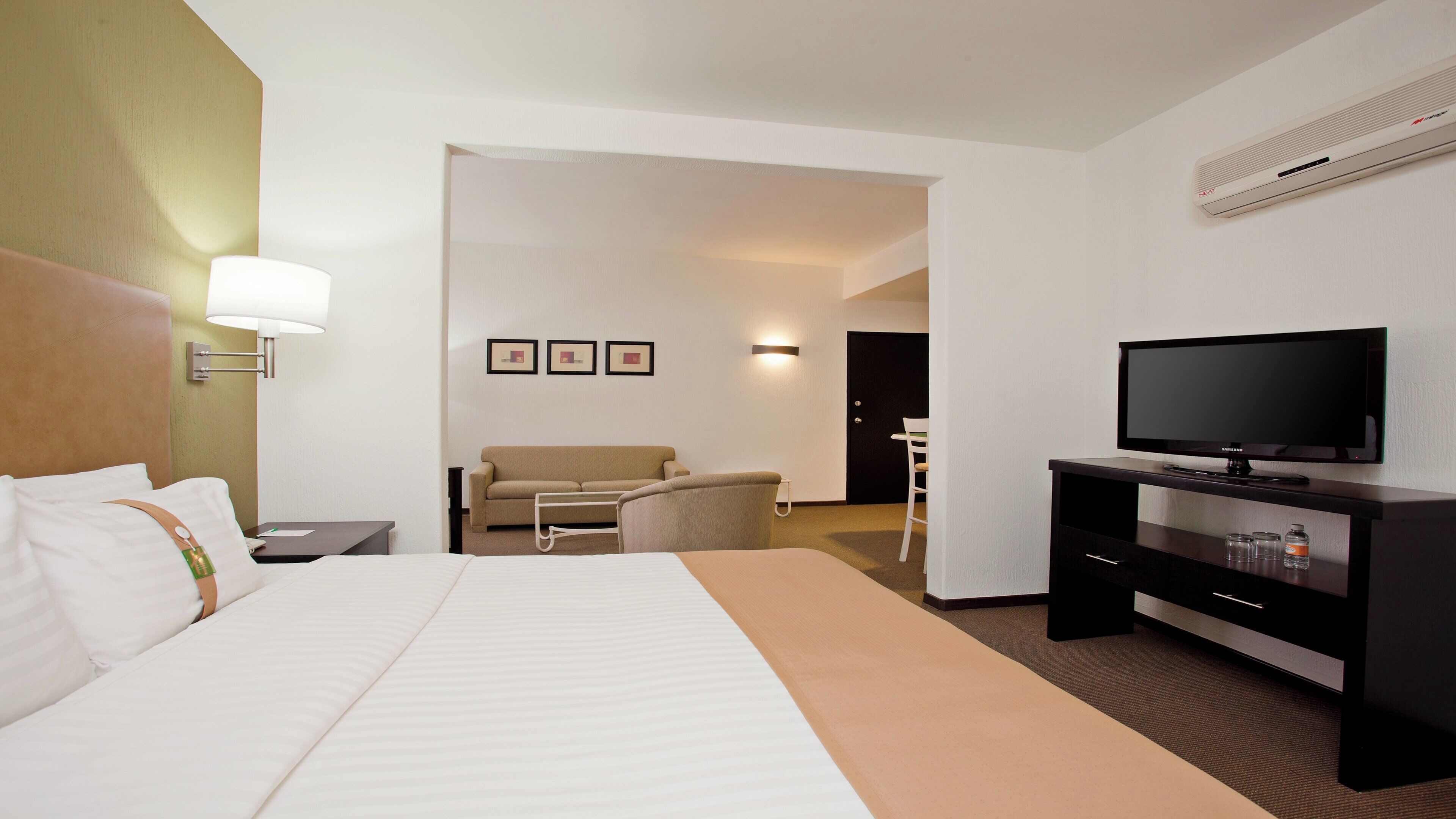 A hotel room with a bed, a desk, a television, and a seating area.