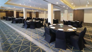 A conference room with round tables, black chairs, and a carpeted floor.