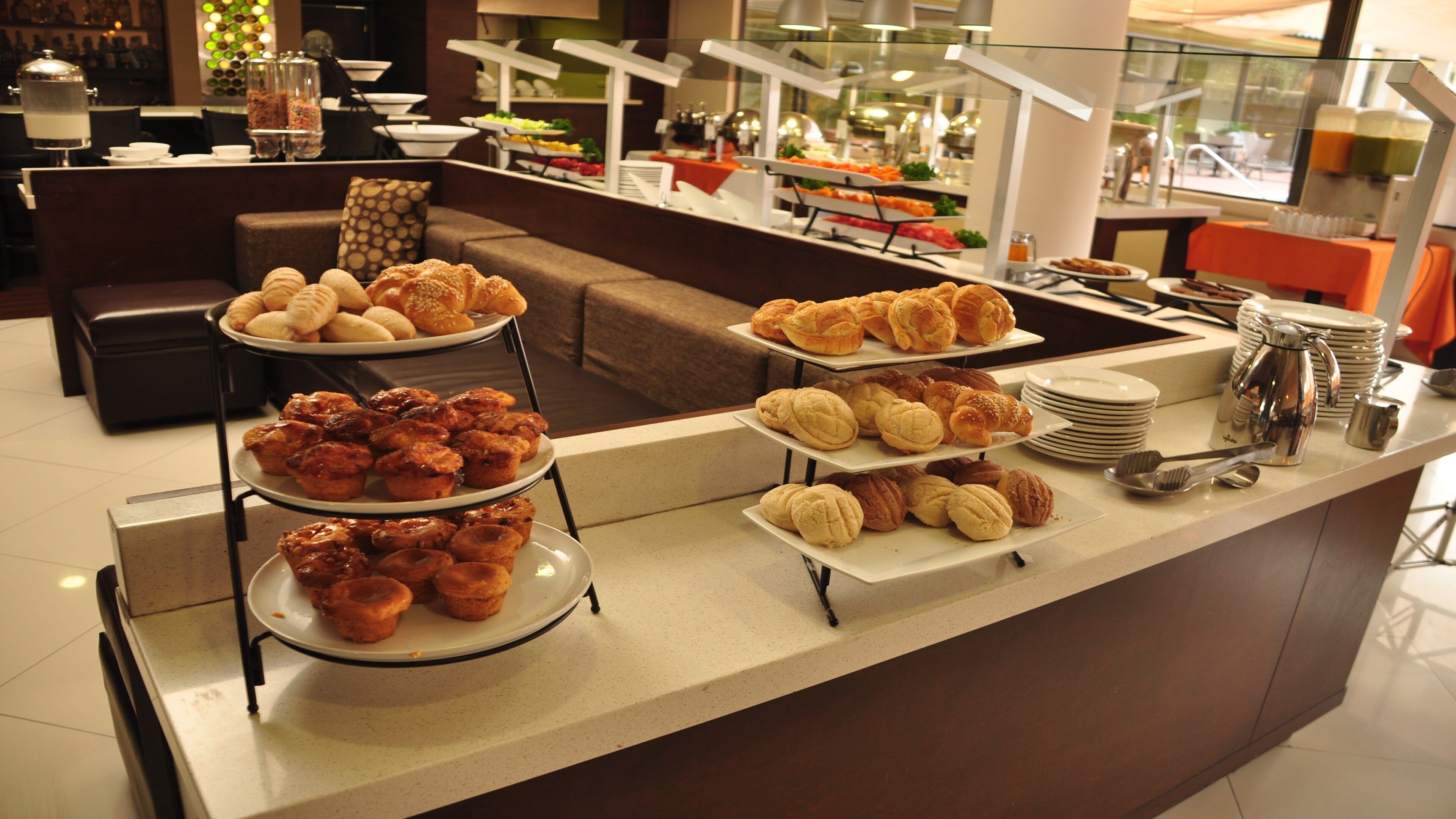 Un área de bufé con varias estaciones de servicio, incluyendo bandejas de pasteles y una estación de café.