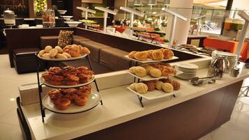 Un área de bufé con varias estaciones de servicio, incluyendo bandejas de pasteles y una estación de café.
