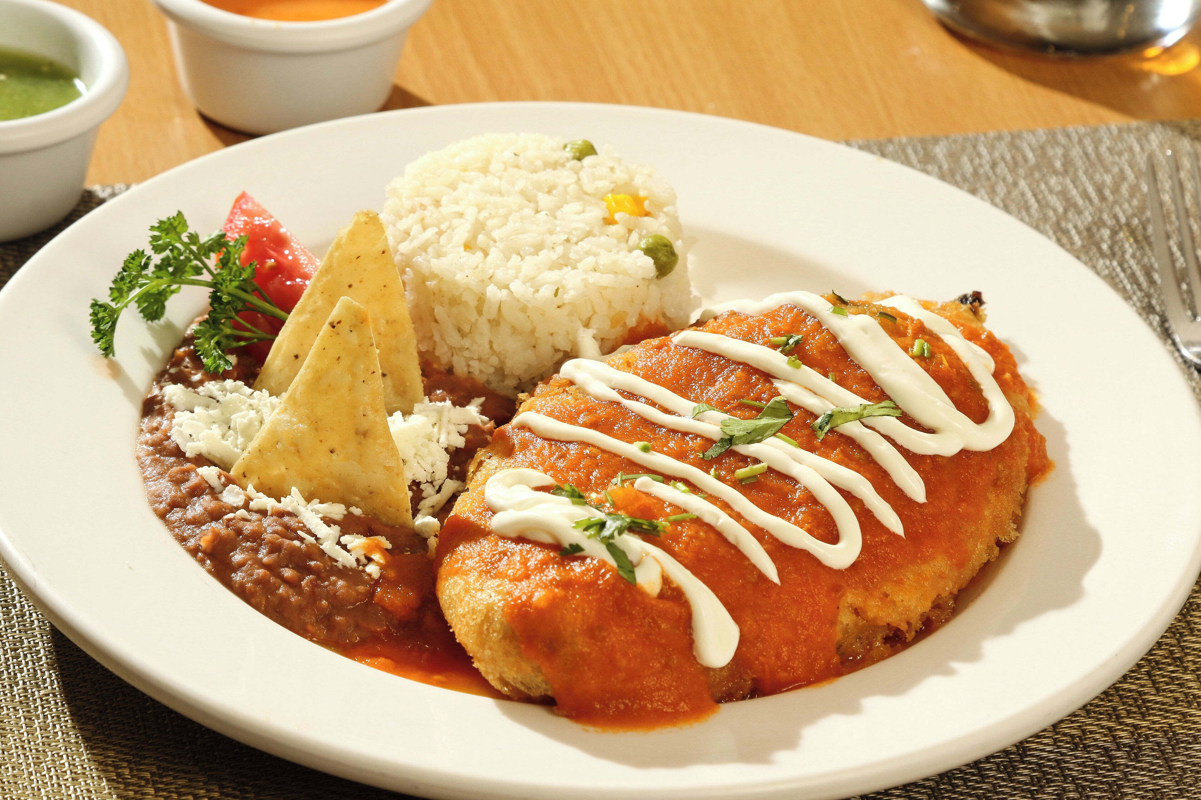A plate of food with rice, beans, a tortilla dish, and a side of salsa.