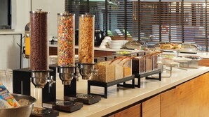 A buffet setup with various food dispensers, including cereal and granola options.