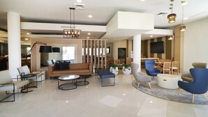 A spacious lobby with a modern design, featuring a mix of seating options including sofas, chairs, and a dining area.