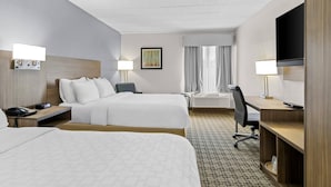 Une chambre d’hôtel avec deux lits, un bureau, une télévision et une fenêtre avec des rideaux.