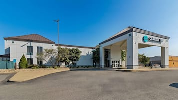Um Clarion Inn com design moderno, apresentando uma entrada coberta e um céu azul límpido.