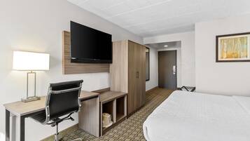 Camera d'albergo con letto, scrivania, sedia, televisione, armadio e un quadro appeso al muro.