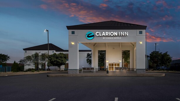 L’entrée d’un hôtel, avec une enseigne indiquant « Clarion Inn by Choice Hotels », sous un ciel crépusculaire.